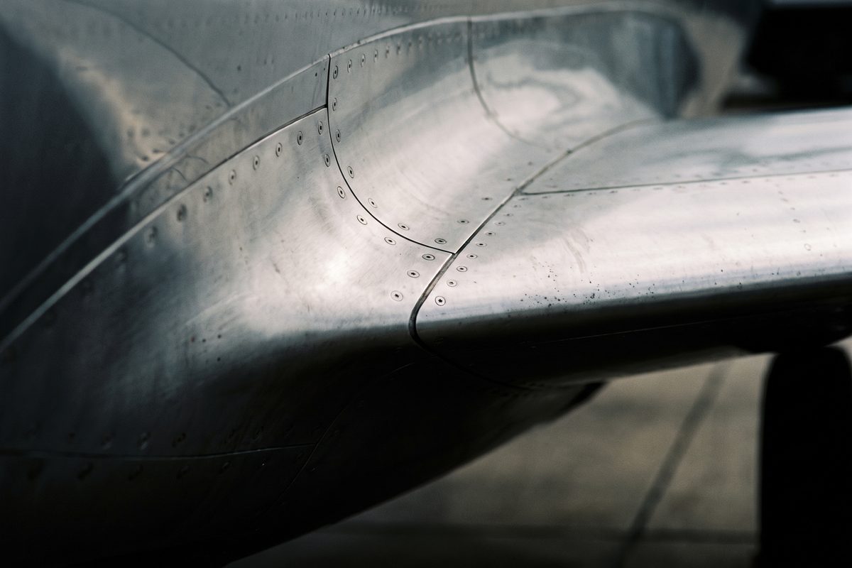 Wing and fuselage of a modern aircraft inside a dark hangar