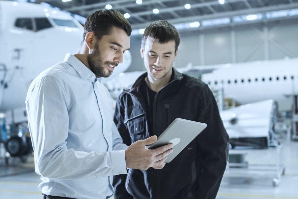 Aircraft maintenance worker and engineer in conversation over a tablet
